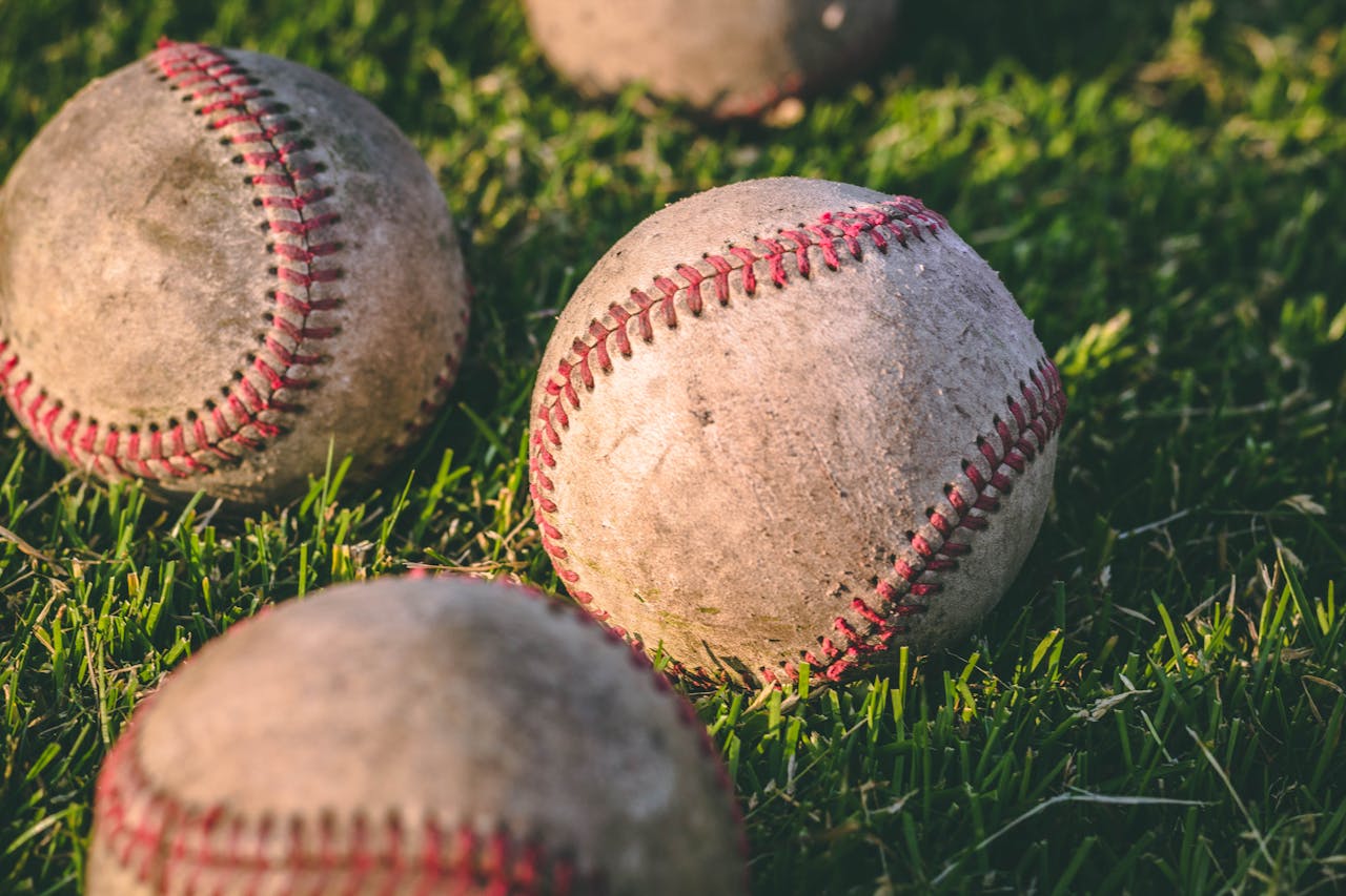 Close Up Photography of Four Baseballs on Green Lawn Grasses